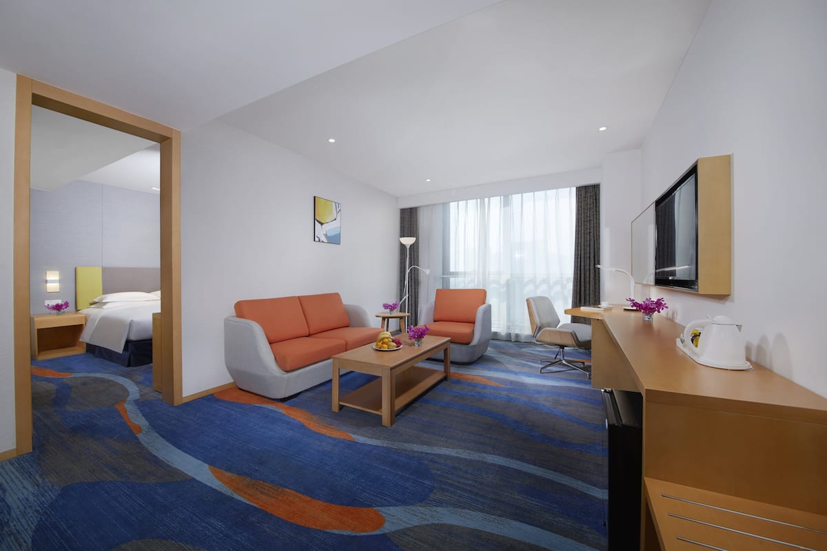 Ein Hotelzimmer mit einem Bett, einem Sofa, einem Couchtisch, einem Schreibtisch und einem Fernseher.