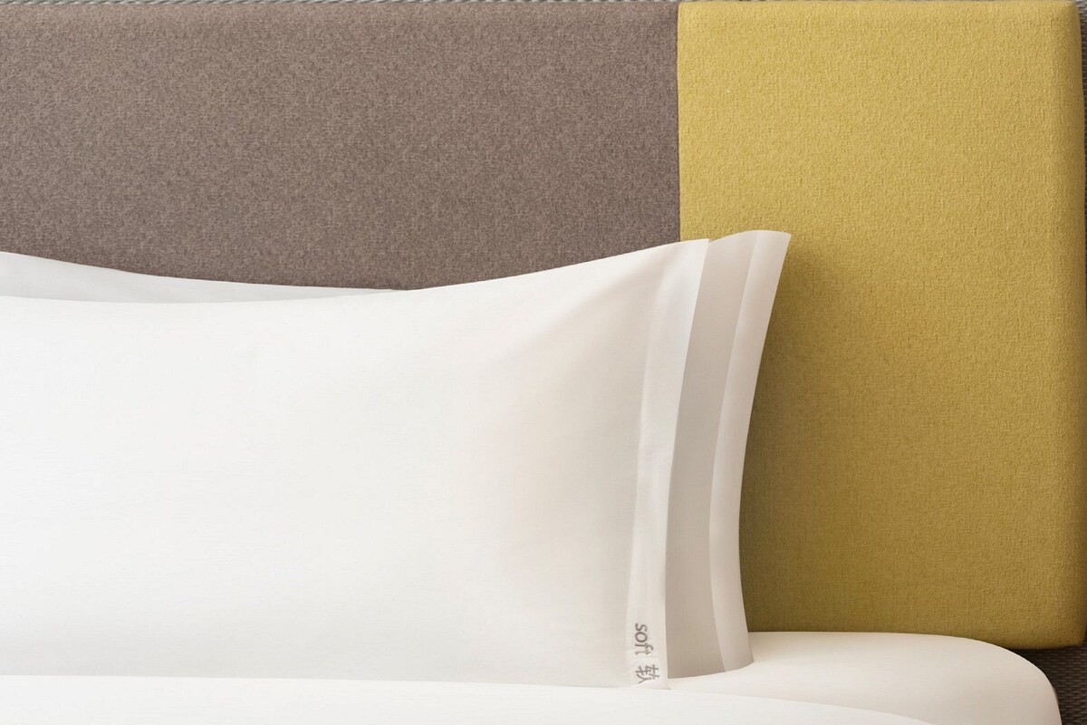 Un lit avec une literie blanche et un oreiller portant une étiquette de marque bien visible.