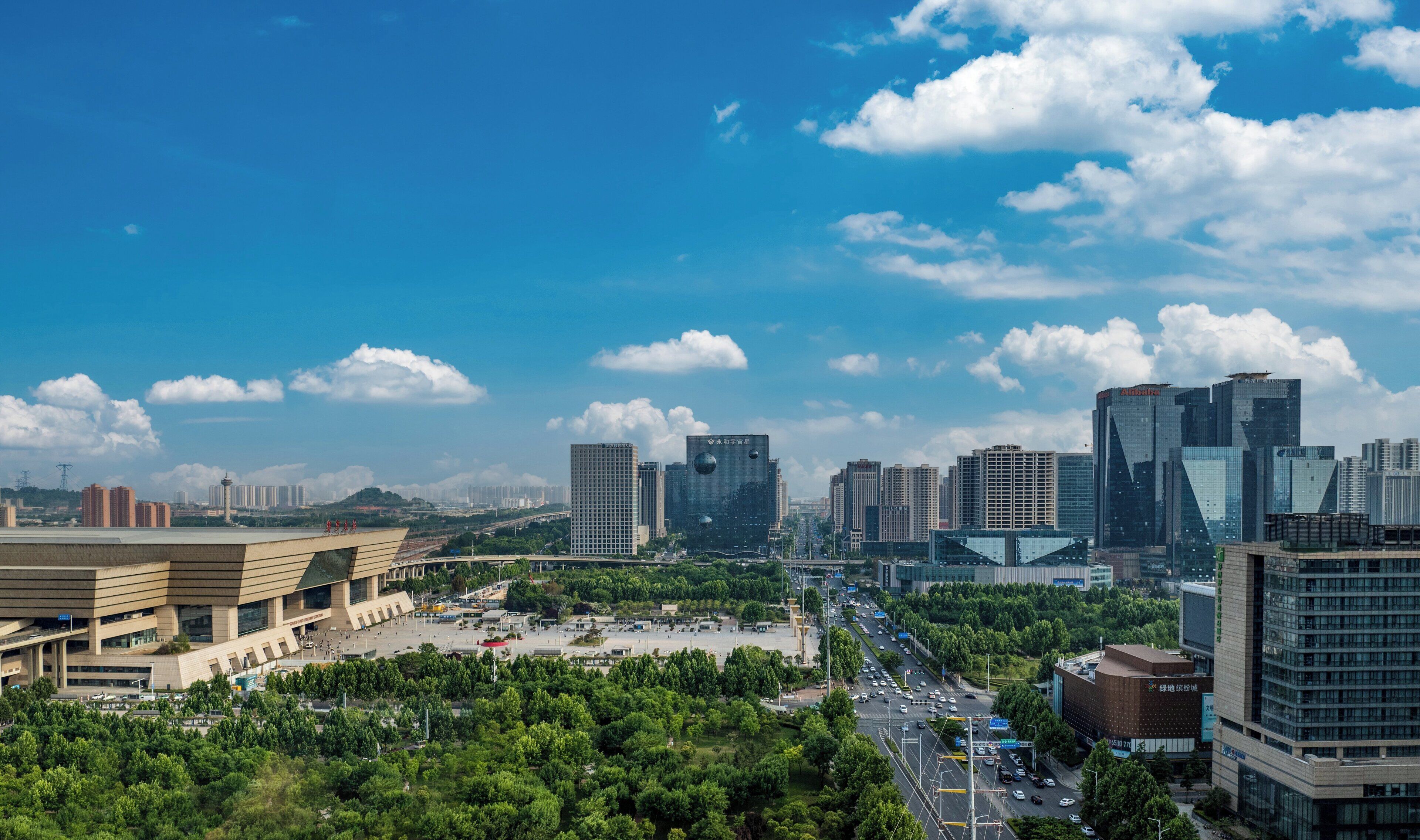 Un paysage urbain avec des bâtiments modernes, une vaste place ouverte et un ciel bleu dégagé.