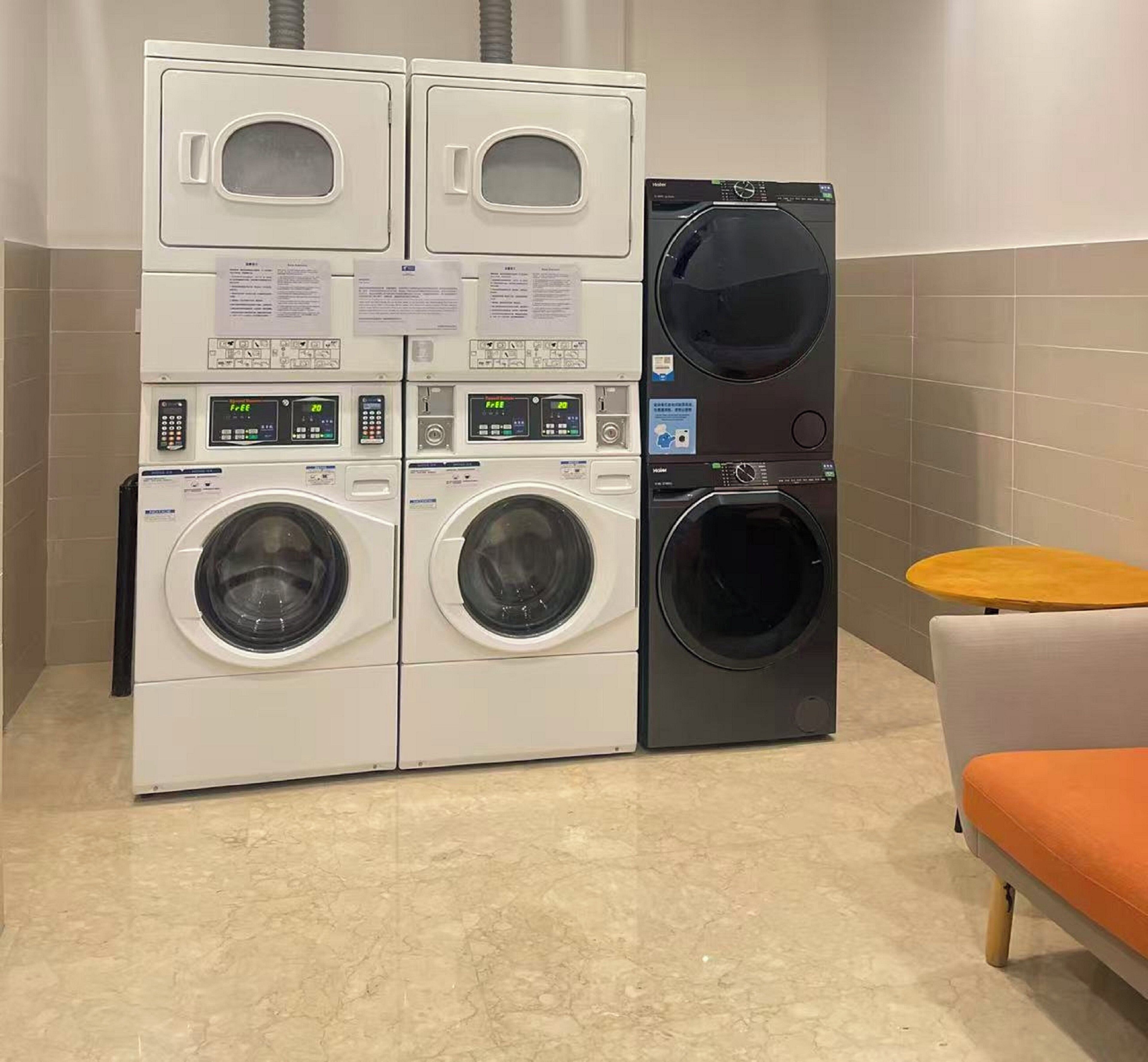 A laundry facility with multiple washing machines and dryers, including a front-loading washer and a top-loading dryer.