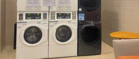 A laundry facility with multiple washing machines and dryers, including a front-loading washer and a top-loading dryer.