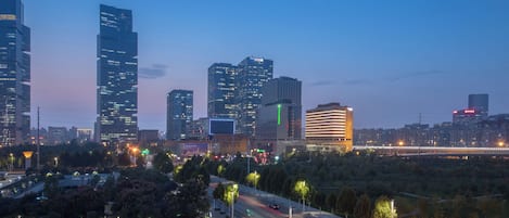 A cityscape with modern high-rise buildings, a highway, and a park area with trees.