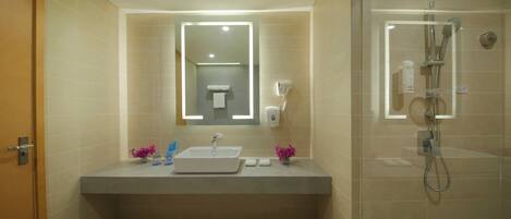 A modern bathroom with a large sink, mirror, and glass-enclosed shower.