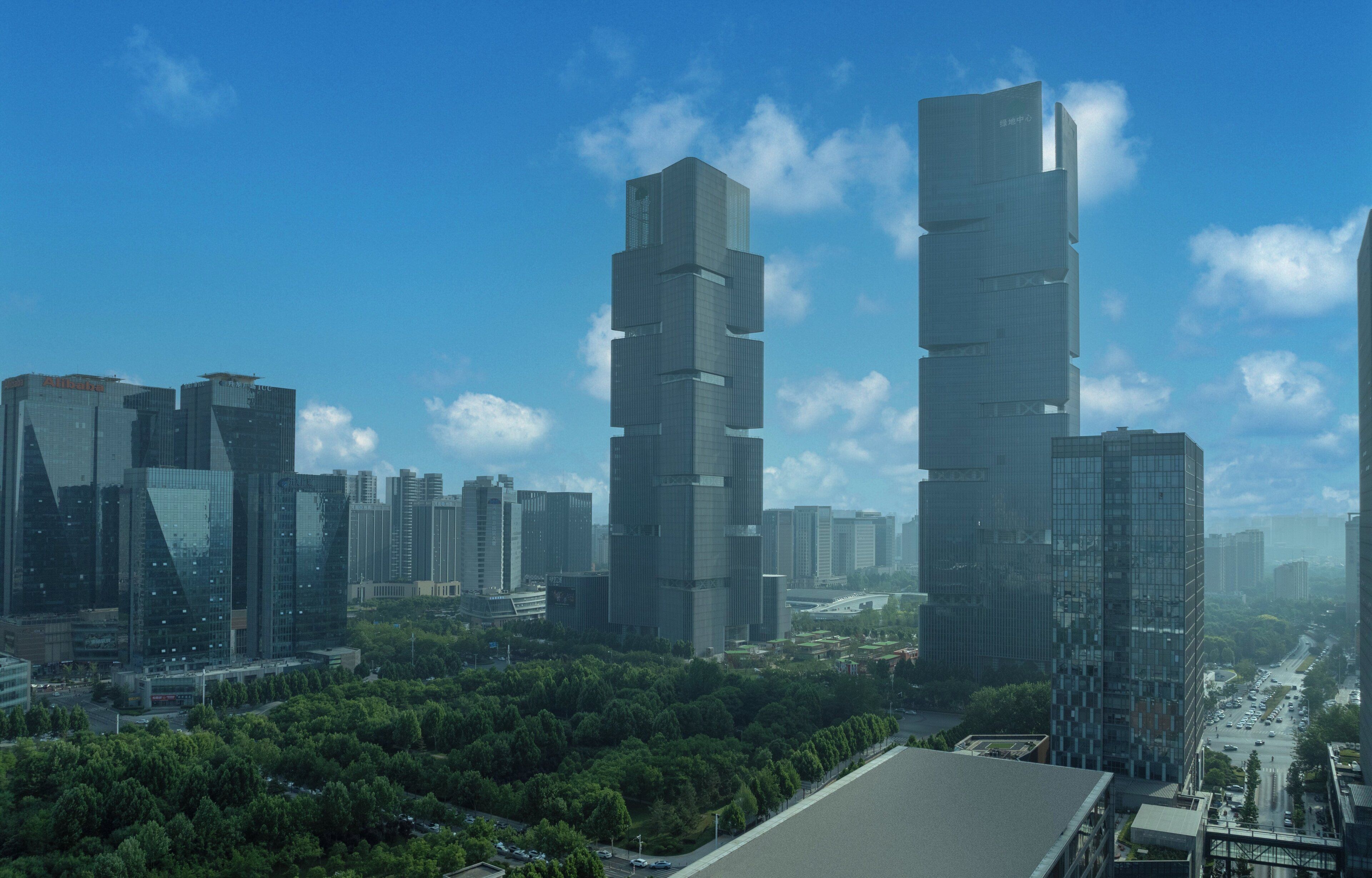 Un paisaje urbano con modernos rascacielos, cielo despejado y una zona verde de parque.