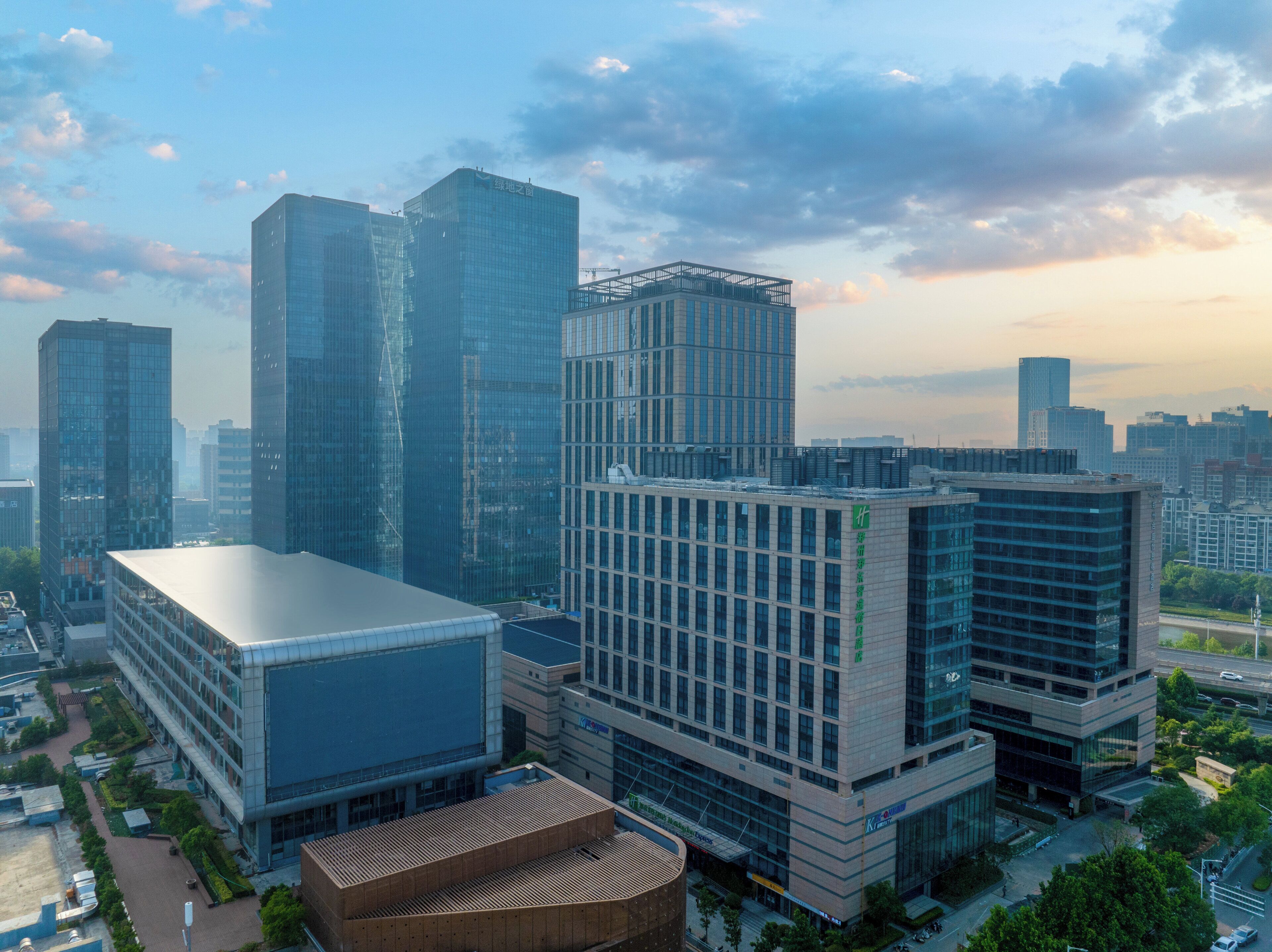 A modern high-rise building complex with multiple office buildings, including a prominent glass-fronted structure and a smaller rectangular building with a flat roof.