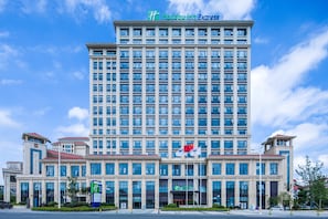 Un hotel grande con varios pisos, un letrero llamativo en la parte superior y varias banderas.