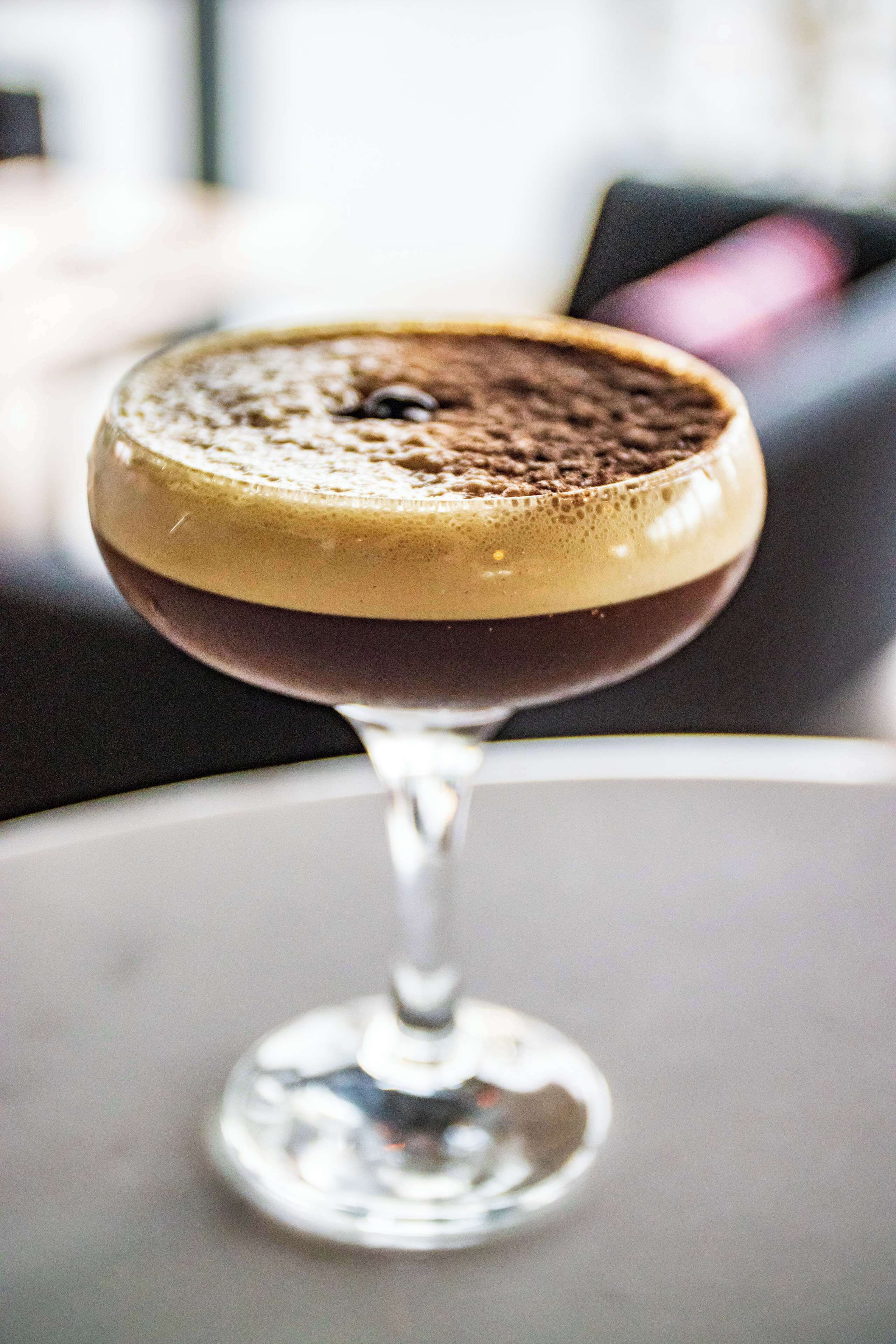 A cocktail in a stemmed glass on a table.