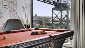 Una mesa de billar con vistas a un puente y al paisaje urbano a través de una ventana.