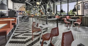 Enjoy a meal in a stylish space with red booths, white tables, and woven chairs, surrounded by a mural and large windows.