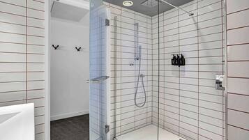 A modern shower area with a glass door, tiled walls, and a showerhead.