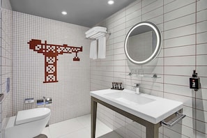 Features a clean, minimalist design with a large mirror, toilet, and towel rack.