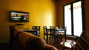A living room with a television, a sofa, a dining table with chairs, and large windows. - Silver Shade (Gulhi)