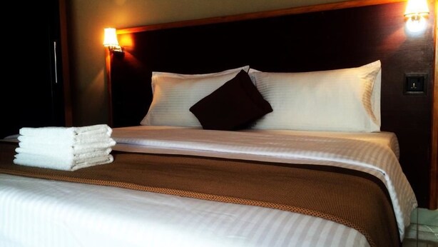 A neatly made bed with white linens and a dark brown headboard. - Silver Shade (Gulhi)