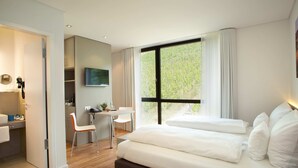 A modern hotel room with a large bed, a desk, and a TV. - Rebgut - Die Weinherberge (Lauda)