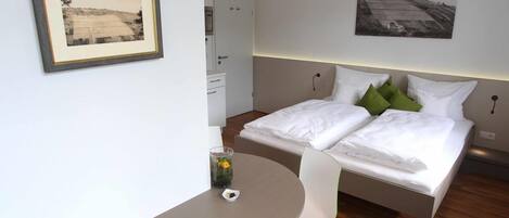A modern bedroom with a bed, bedside tables, a round table, and two framed pictures on the wall.