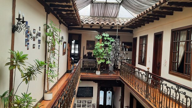 A spacious atrium with a high ceiling, a central staircase, and multiple levels. - La Posada Cuencana (Cuenca)