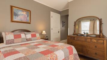 Quarto com cama, penteadeira e um quadro na parede.