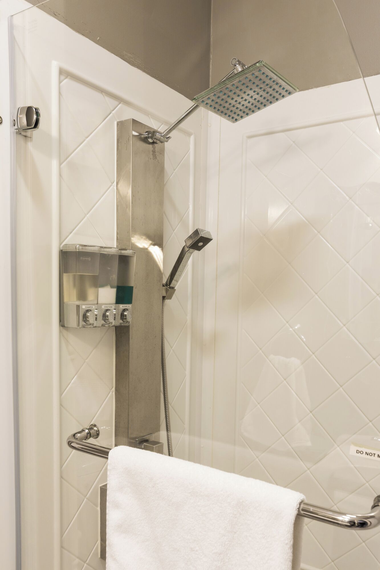 Eine Dusche mit Duschbrause, einer fest installierten Bedienung und einem Handtuchhalter.