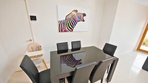 A dining area with a table, chairs, a zebra artwork, and a white chair with a baby seat.