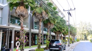 Un bâtiment moderne avec une façade en verre, des palmiers et un SUV garé devant.