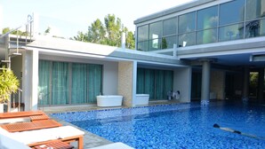 Un hôtel moderne doté d’une piscine, de chaises longues et d’un espace spa.
