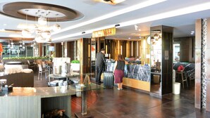 Un hall d’hôtel comprenant un comptoir d’accueil, un espace salon et un design moderne au niveau du plafond.