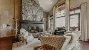 A cozy living room with a stone fireplace, comfortable seating, and a view of the city.