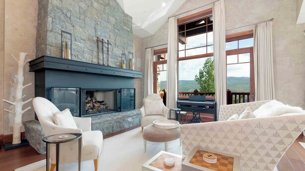 A spacious living room with a stone fireplace, comfortable seating, and a view of the outdoors.