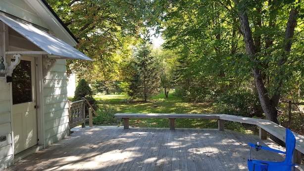 A wooden deck with a bench, surrounded by trees and a grassy area. - Manchester Walking distance to all shops and restaurants quick ride/lakes |hikes (manchester center)