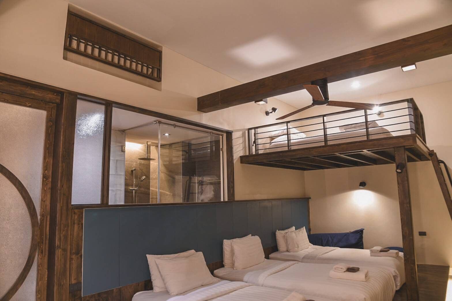 Una habitación con dos camas, una litera, una ducha y un espejo grande.