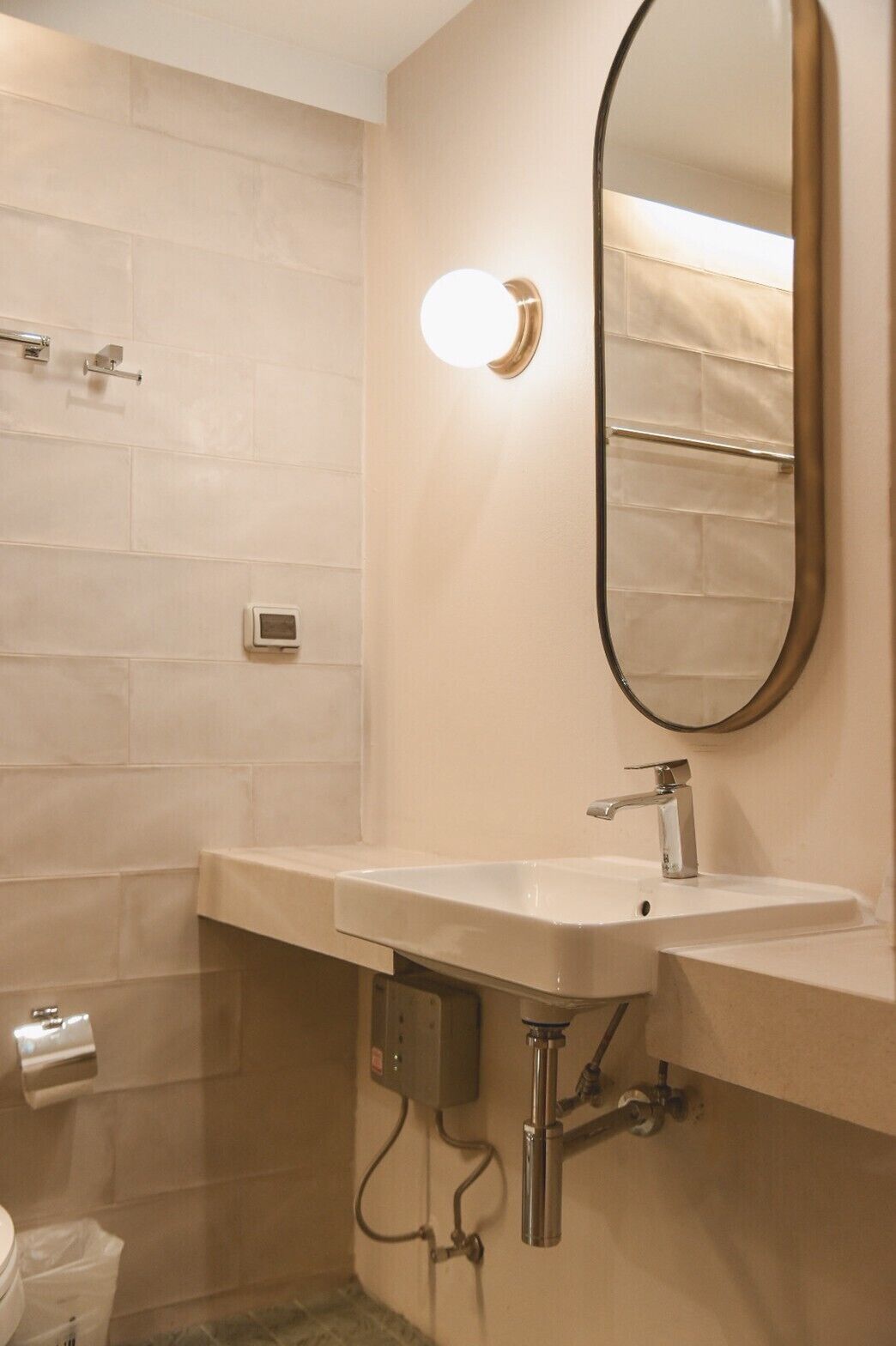 Un baño con lavamanos blanco, un espejo y un perchero para toallas.