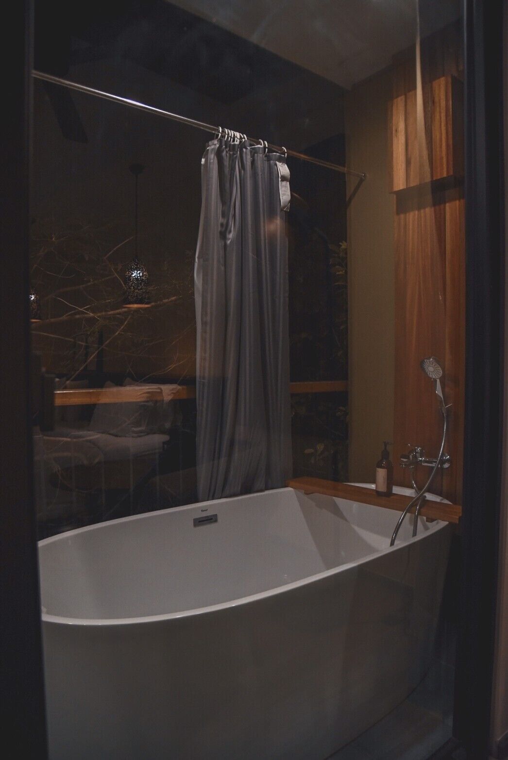 A modern bathroom with a freestanding bathtub, wooden paneling, and a glass shower enclosure.