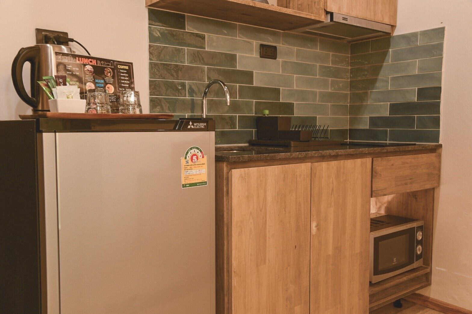 A compact kitchen with a refrigerator, a microwave, and a sink.