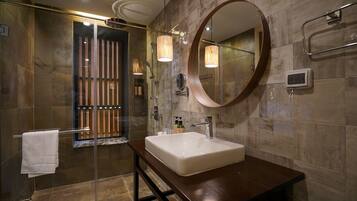 Un baño moderno con cabina de ducha de vidrio, un espejo grande y un mueble de tocador de madera.
