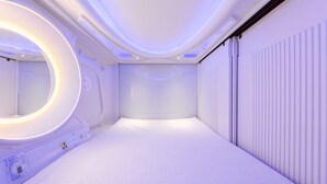 Una habitación moderna y minimalista con una cama grande, un aplique circular y un radiador.