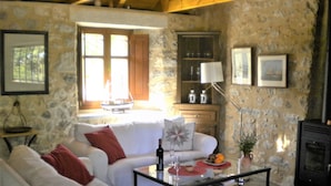 Ein gemütliches Wohnzimmer mit Steinwand, einem weißen Sofa, einem Couchtisch und einem Kamin.