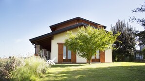 A two-story house with a sloped roof, a front porch, and a tree in the yard.