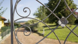 A wrought iron gate with a floral design, leading to a pathway in a landscaped area.