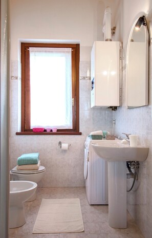 A bathroom with a toilet, sink, and window. - Panoramic apartment in villa with garden (Parella)