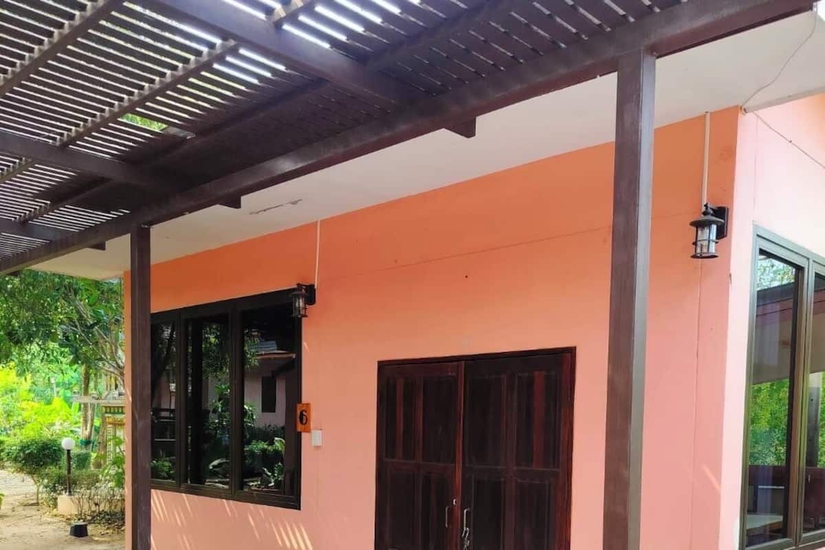 Un porche cubierto con piso de baldosas y mobiliario exterior.