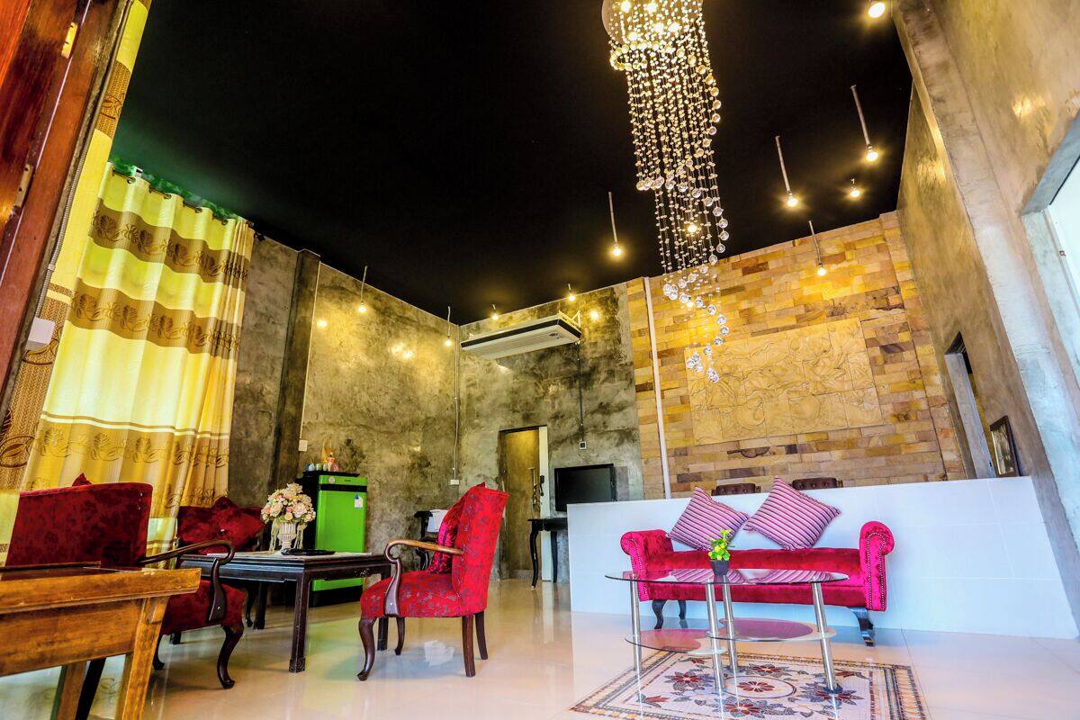 Un vestíbulo amplio con un sofá rojo, un escritorio verde y un candelabro.