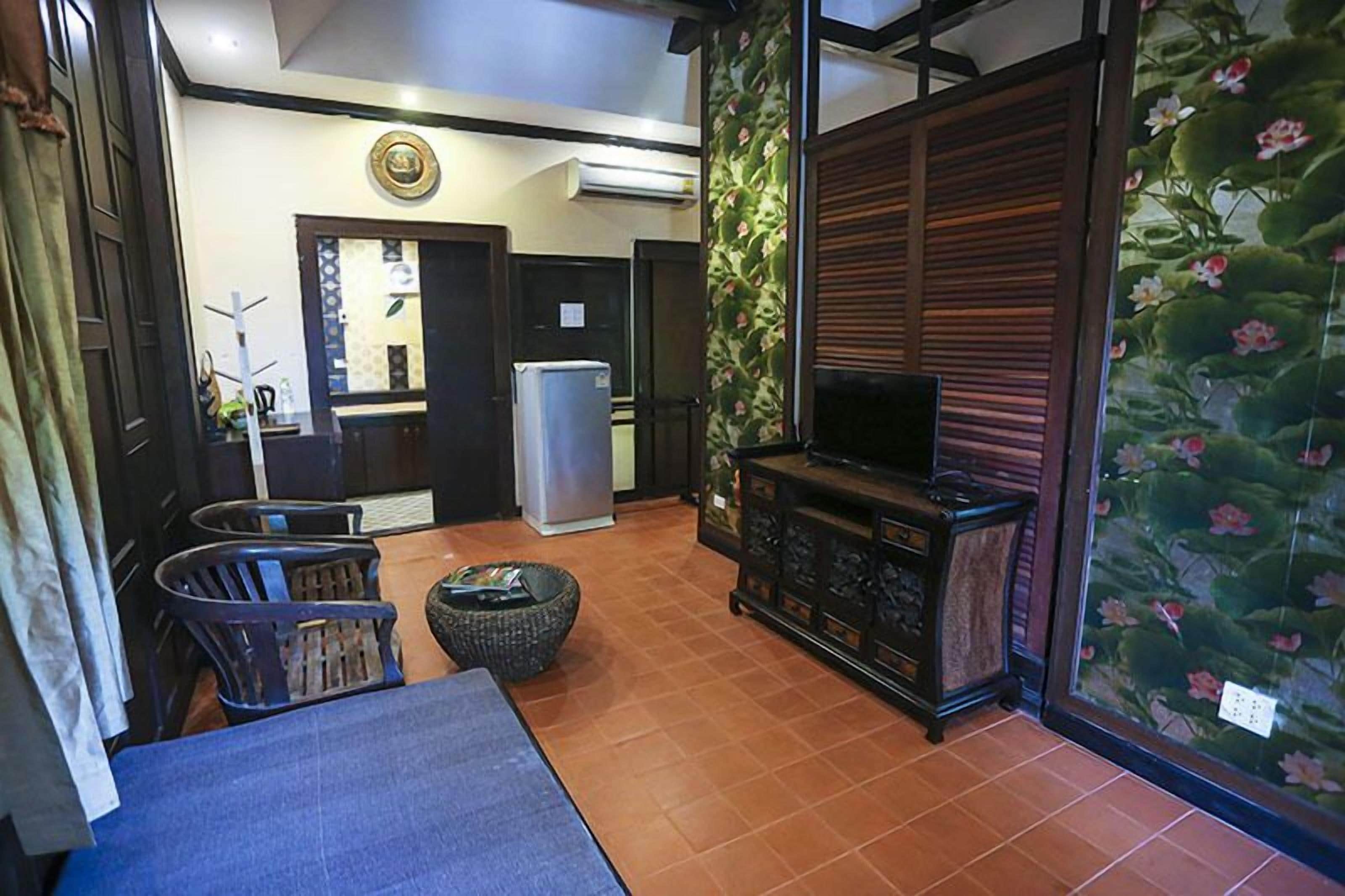 Una sala de estar con televisor, una mesita y un muro decorativo con motivos florales.