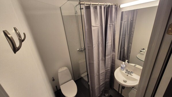 Une salle de bain avec des toilettes, un lavabo et un rideau de douche.