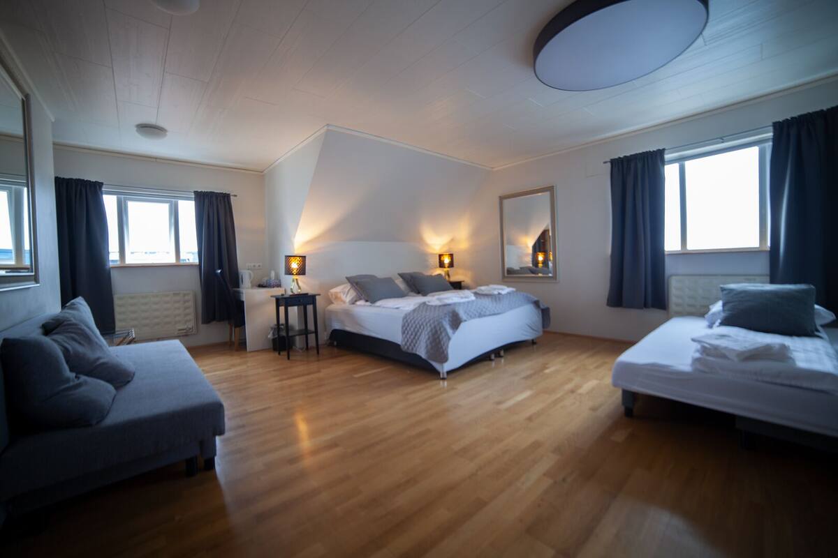A spacious bedroom with a large bed, a desk, and a sofa.