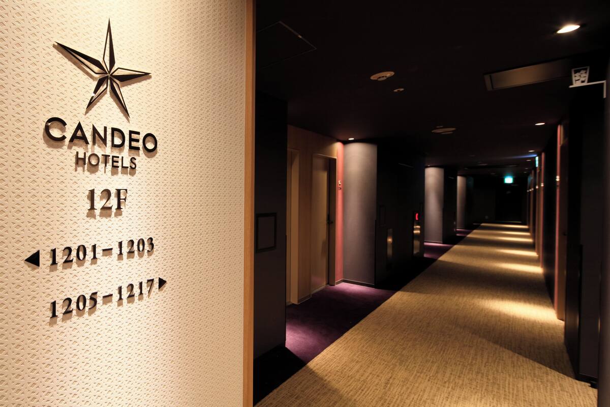 A hotel corridor with directional signs for rooms 1201-1203 and 1205-1217, and a star logo above the hotel name.