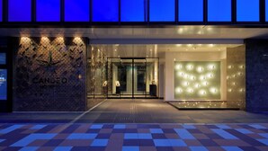 Een hotelentree met een modern ontwerp, met een gebeeldhouwde gevel en een glazen deur.