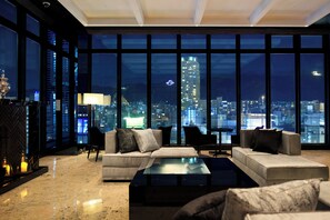 A modern living room with a large city view, a fireplace, and a glass coffee table. - Candeo Hotels Kobe Torroad (Kobe)