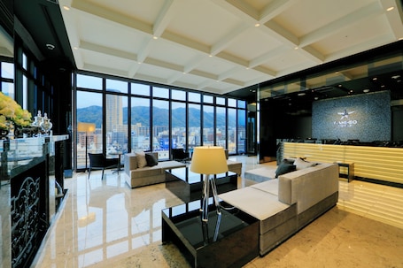 A modern hotel lobby with a large seating area, a reception desk, and a view of the cityscape.. Candeo Hotels Kobe Torroad