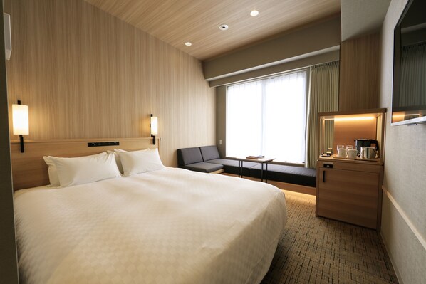 A hotel room with a large bed, a sofa, a desk, and a mirror. - Candeo Hotels Kobe Torroad (Kobe)