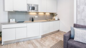 Una cocina moderna con armarios blancos, un microondas integrado y un fregadero.